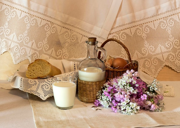 Bodegón La canasta con huevos y flores silvestres leche y pan en el primer plano de la mesa