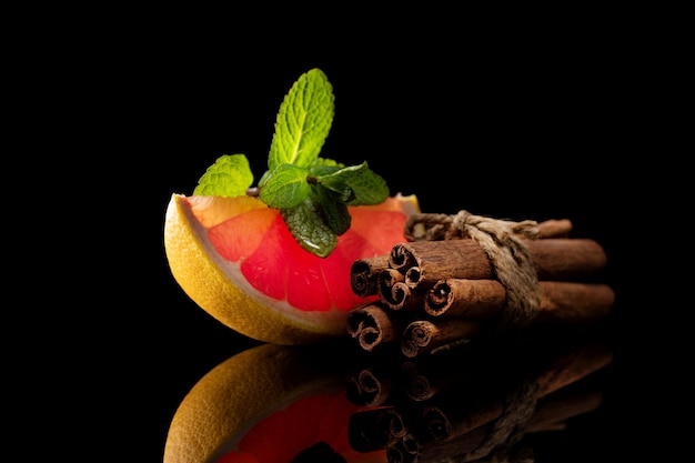 Bodegón de canela naranja roja y menta aislado sobre fondo negro