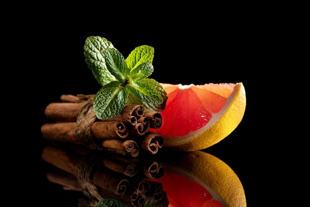 Bodegón de canela naranja roja y menta aislado sobre fondo negro