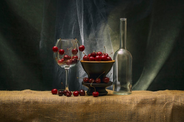 Bodegón con cerezas maduras en vaso y jarrón