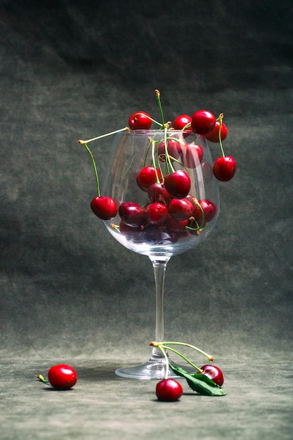 Bodegón con cerezas rojas maduras en un vaso grande