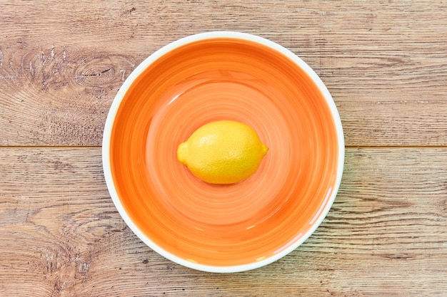Bodegón de color - limón amarillo sobre una placa naranja sobre una mesa de madera