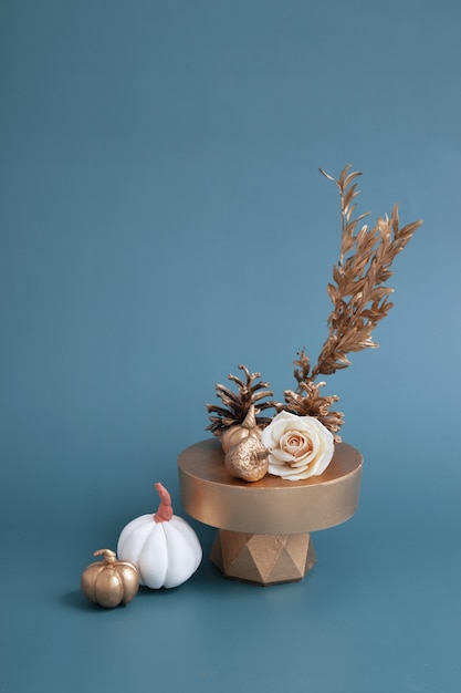 Bodegón creativo de calabazas blancas y doradas, bellotas y rosa sobre un fondo turquesa. Concepto de otoño minimalista