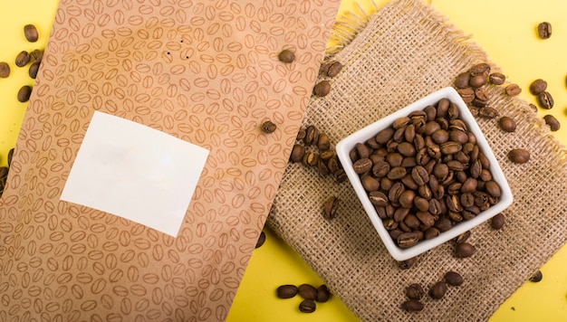 Bodegón de envases de café sin marca en diferentes colores y fondos naturales junto a tazas, cafetera y café.