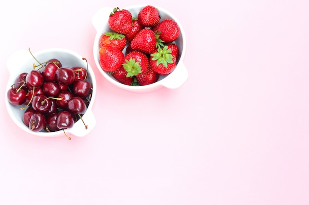 Bodegón con fresas y cerezas sobre fondo rosa