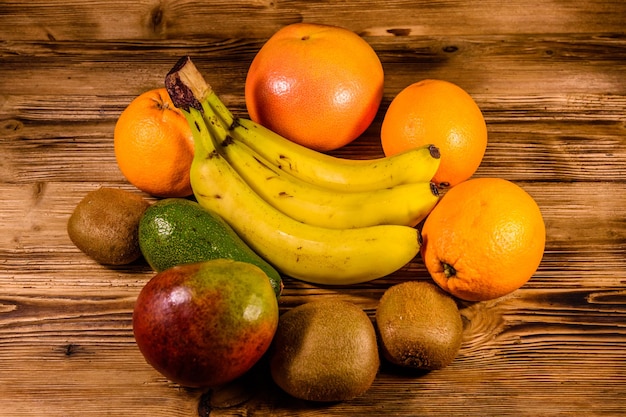 Bodegón con frutas exóticas. Plátanos, mango, naranjas, aguacate, pomelo y kiwis en la mesa de madera rústica