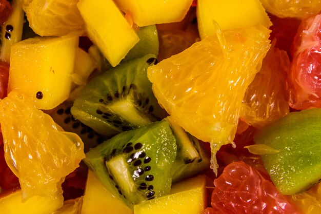 Bodegón con frutas exóticas, plátanos, mangos, naranjas, pomelos y kiwis en una mesa de madera rústica