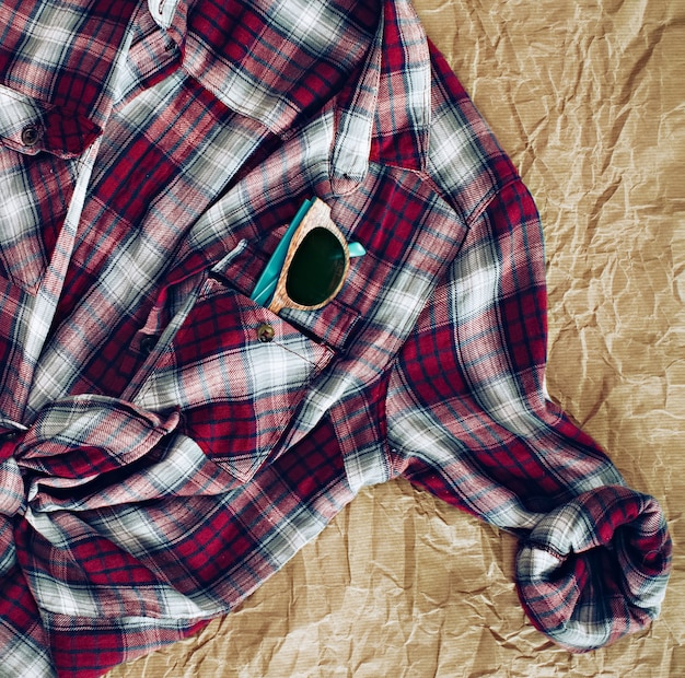 Foto bodegón de gafas de sol en el bolsillo de la camisa a cuadros como se ve desde arriba