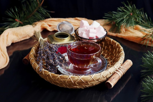 Bodegón de invierno una bandeja decorativa con una taza de té y un ramo de lavanda sobre un fondo oscuro una servilleta amarilla ramas de pino reflejo de los objetos