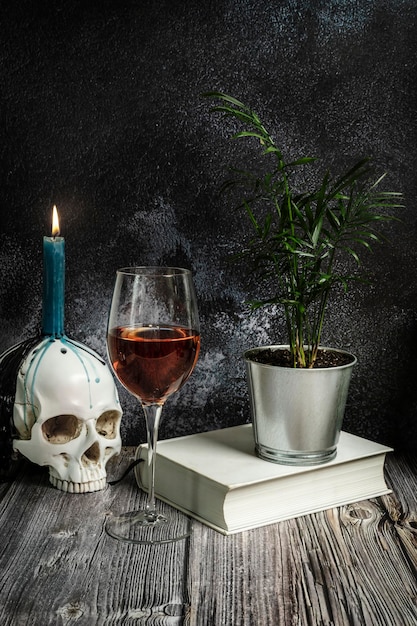 Bodegón del lector borracho con planta copa de clarete papel blanco y vela con calavera