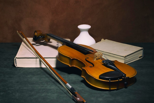 Bodegón con libros de violín y un jarrón blanco.