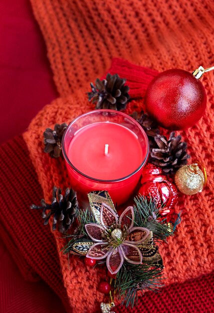 Bodegón navideño Foto de temporada Vela conos de pino Bolas de Navidad sobre fondo rojo tejido