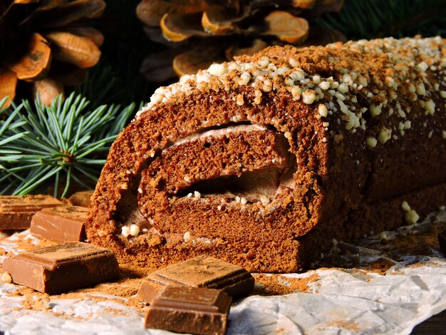 Bodegón navideño. Navidad chocolate Yule Log. Ramas de los árboles de Navidad y conos. Trozos de chocolate.