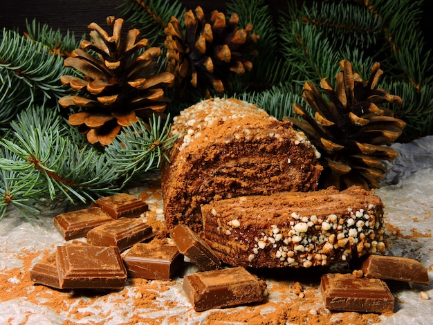 Bodegón navideño. Navidad chocolate Yule Log. Ramas de los árboles de Navidad y conos. Trozos de chocolate.