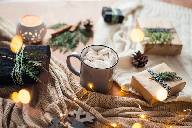 Bodegón navideño con tazas de café, cajas de regalo y velas.