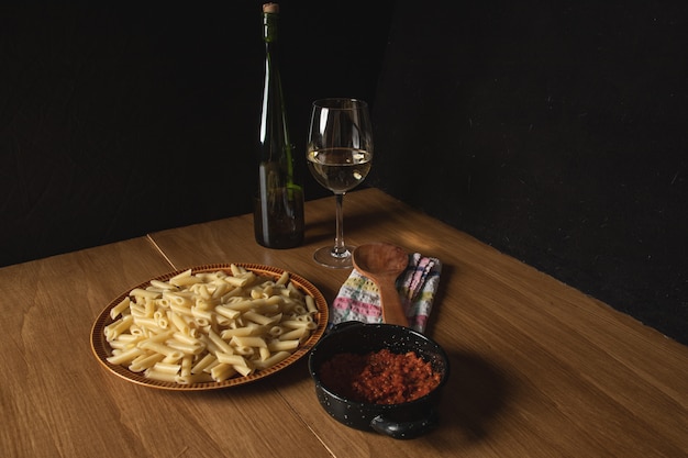Foto bodegon of makkaroni-teller mit bolognese-sauce und geriebenem käse und einem glas wein dazu.