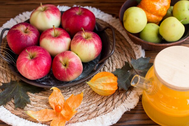 Bodegón otoñal con calabaza physalis y espiguillas Concepto de un pueblo sobre un fondo de madera con manzanas y hojas de arce