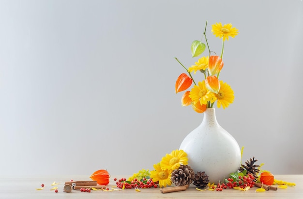 Bodegón otoñal con flores, conos, bayas en estante de madera.