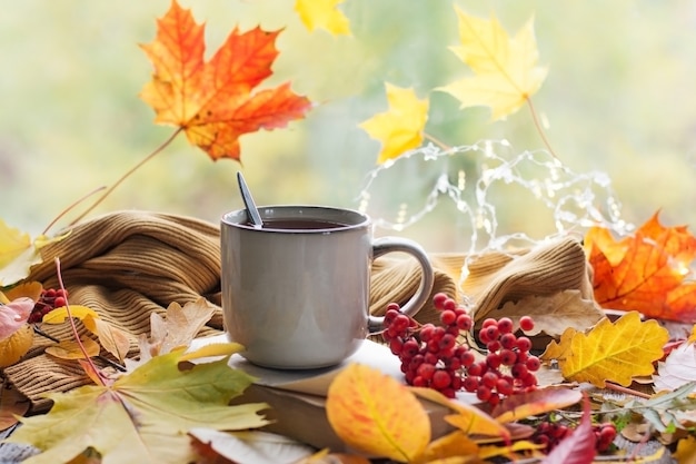 Bodegón otoñal con un hermoso bokeh. Hojas de otoño y una taza de café o té humeante, calabazas y una cosecha de otoño. Estacional, café de la mañana, descanso dominical y el concepto de naturaleza muerta.