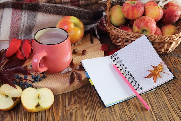 Bodegón otoñal con una taza de cacao, cuaderno y manzana.