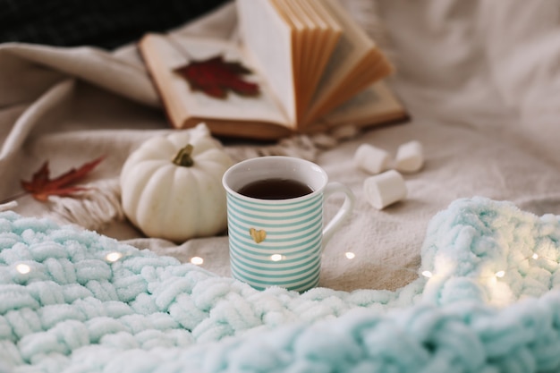 Bodegón otoñal con una taza de café, flores y calabazas en un acogedor plaid