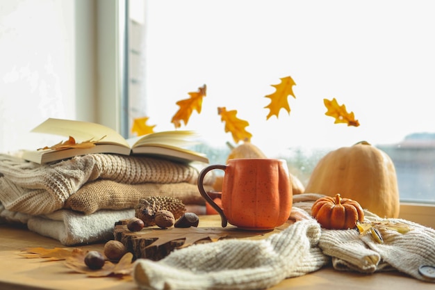 Foto bodegón de otoño en el alféizar de la ventana una taza de té velas calabazas hojas interior de la casa de acción de gracias