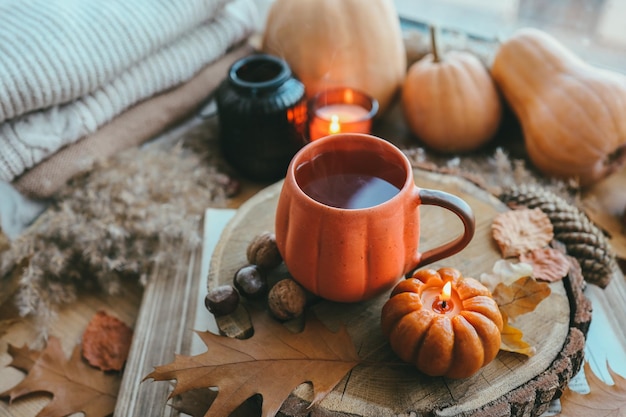 Bodegón de otoño en el alféizar de la ventana una taza de té velas calabazas hojas interior de la casa de acción de gracias