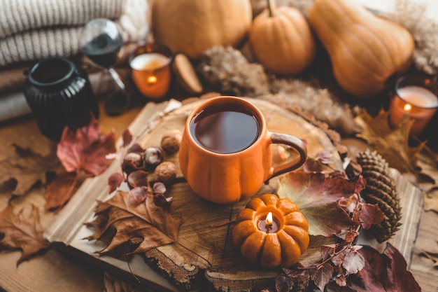 Bodegón de otoño en el alféizar de la ventana una taza de té velas calabazas hojas interior de la casa de acción de gracias