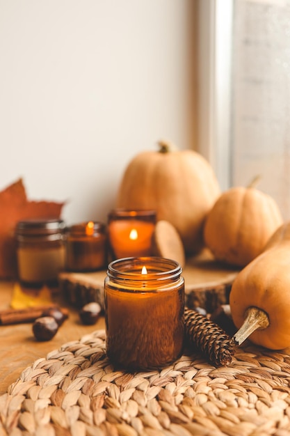 Bodegón de otoño en el alféizar de la ventana una vela encendida calabazas y velas