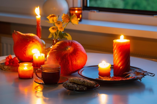 bodegón de otoño con calabazas, velas encendidas y taza de té