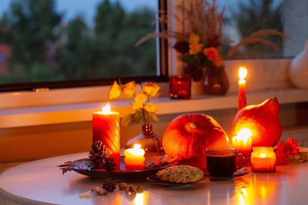 bodegón de otoño con calabazas, velas encendidas y taza de té