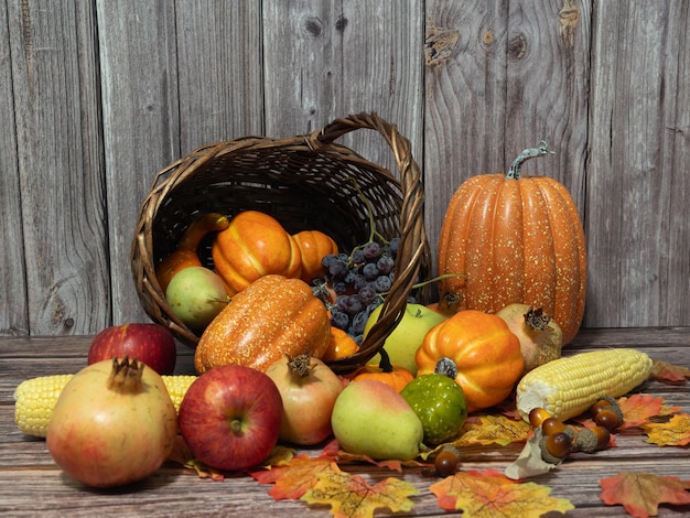 Bodegón de otoño Diferentes frutas, verduras y calabaza en la cesta de mimbre sobre la mesa de madera