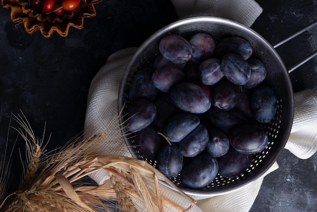 Bodegón de otoño dramático con ciruelas y calabaza sobre un fondo oscuro