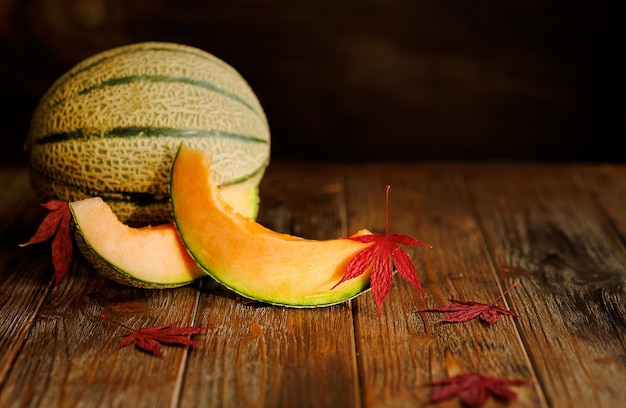 Bodegón de otoño con melón en una llave oscura sobre un fondo de madera