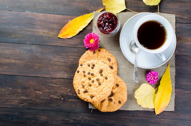 Bodegón de otoño con taza de té, galletas y hojas.