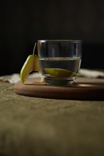 Bodegón con una pera mordida y un vaso de agua en colores cálidos