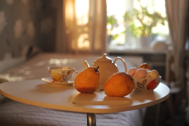 Foto bodegón peras tetera tazas dulces en el fondo de la habitación