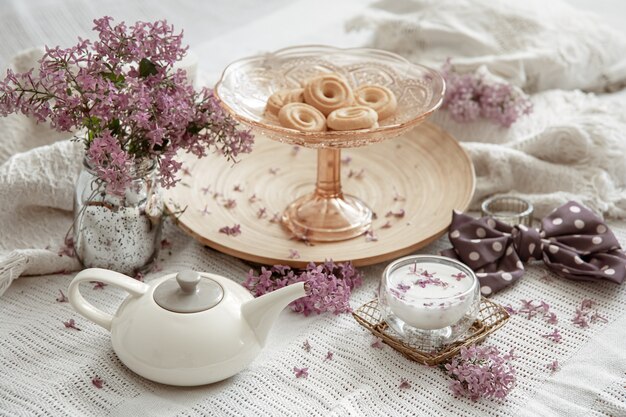 Bodegón de primavera con flores lilas, dulces, leche y detalles decorativos