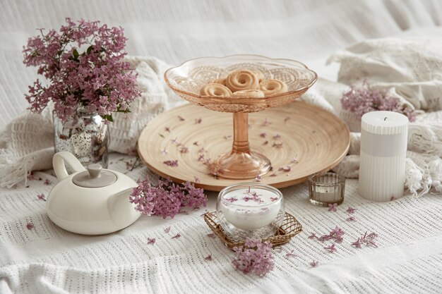 Bodegón de primavera con flores lilas, dulces, leche y detalles decorativos