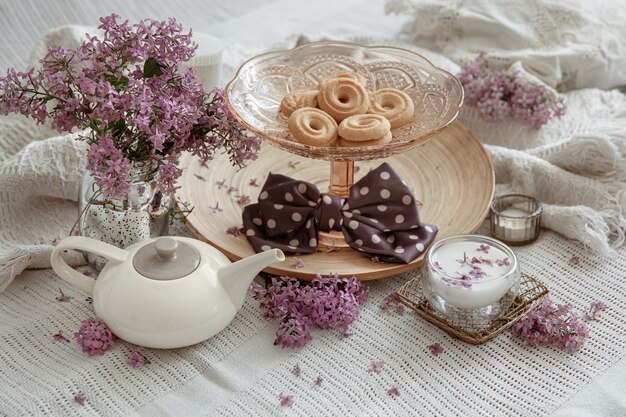 Bodegón de primavera con flores lilas, dulces, leche y detalles decorativos