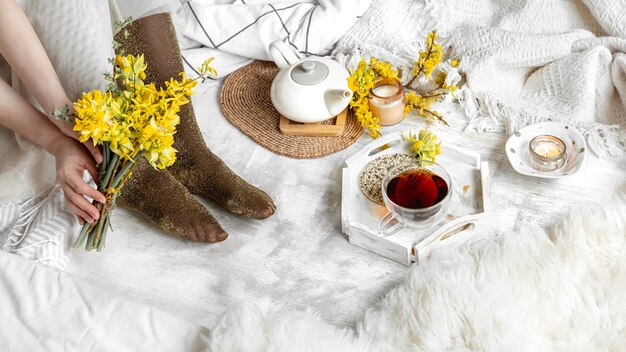 Bodegón de primavera con una taza de té y flores amarillas. Acogedora casa.