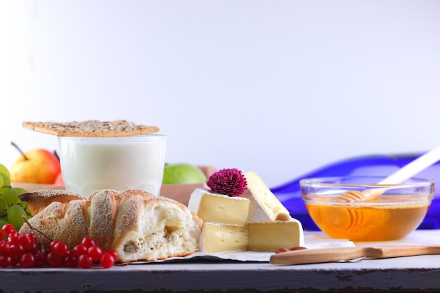 Bodegón de queso miel nueces fruta y una botella azul sobre un fondo borroso Comida para un bocadillo saludable y sabroso en un pergamino blanco Primer plano