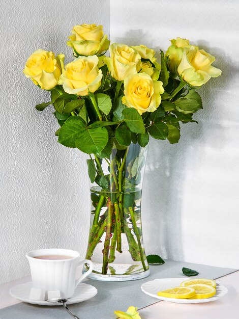 Bodegón con un ramo de rosas amarillas y una taza de té.