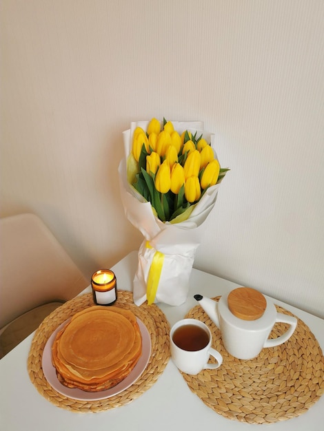 Bodegón con un ramo de tulipanes una tetera una taza de tortitas de té y una vela