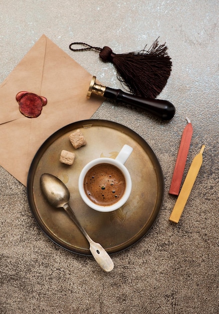Bodegón retro con taza de café espresso, sobre con sello de cera y sello de cera