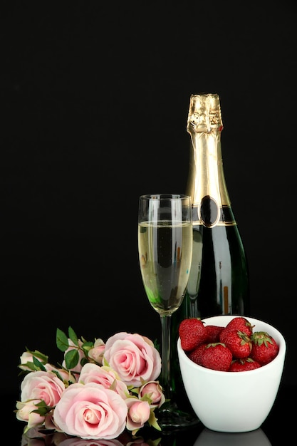 Bodegón romántico con champagne, fresas y rosas rosadas, aislado en negro