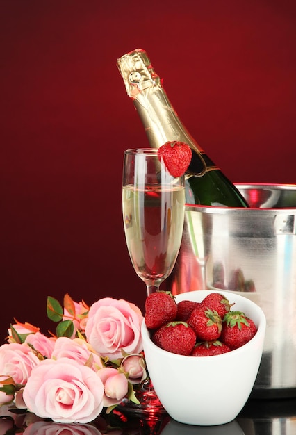 Bodegón romántico con champagne, fresas y rosas rosadas, sobre fondo de color oscuro