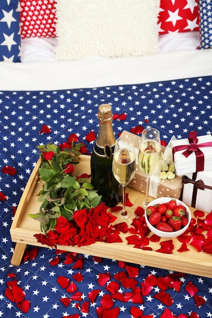 Bodegón romántico con champán fresa y rosas en la cama