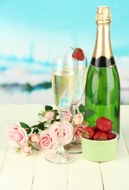 Bodegón romántico con champán fresa y rosas rosadas sobre fondo brillante