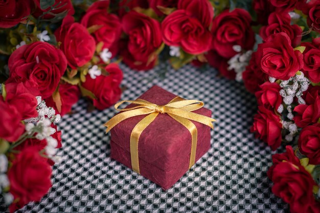 Bodegón romántico pequeña caja de regalo y rosas rojas sobre un fondo de seda para el día de cumpleaños de San Valentín